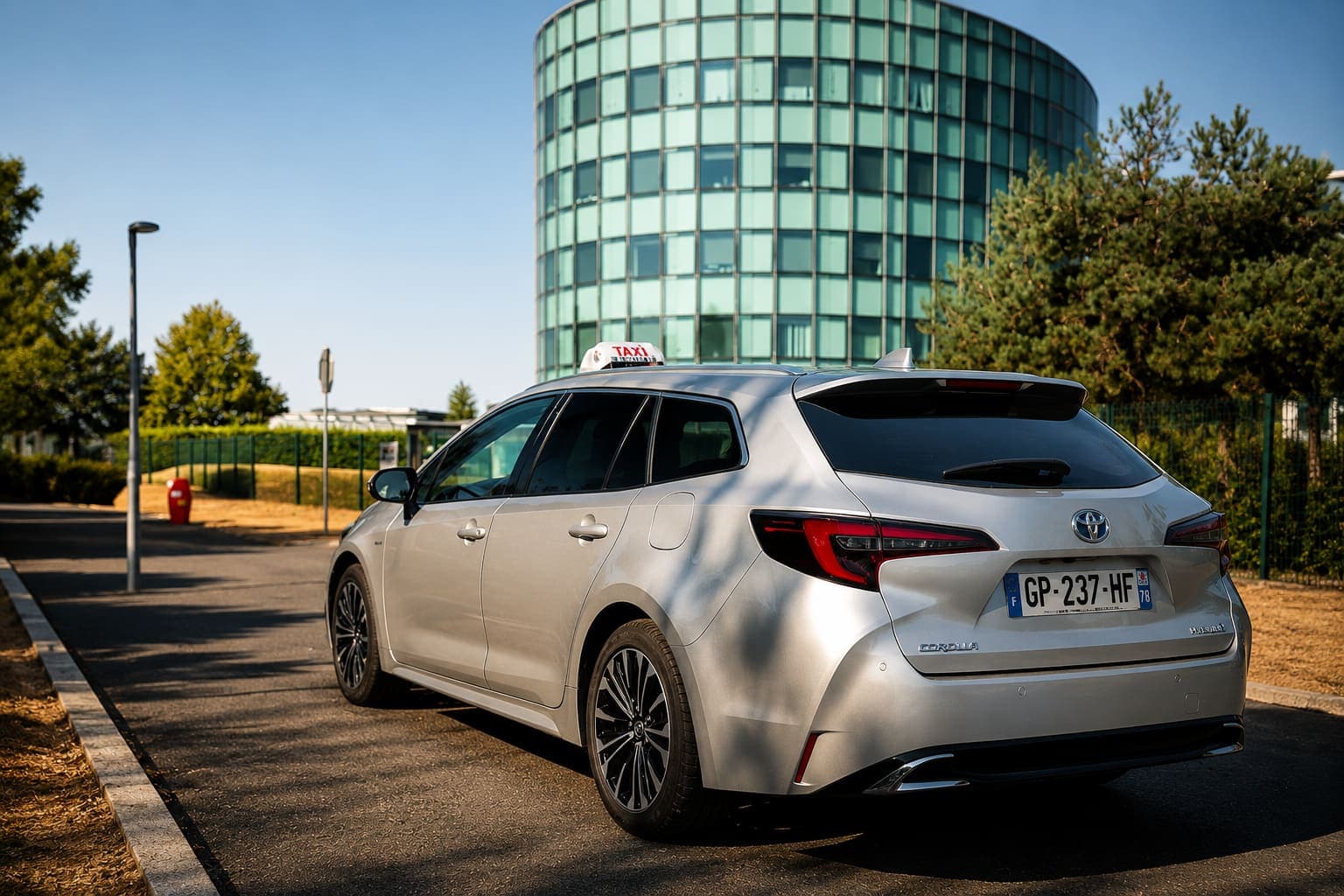 L'Amotaxi, Toyota Corolla grise, devant un immeuble de bureaux